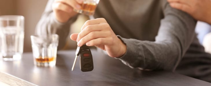 A man holding a car keys and in another hand glass of alcohol 