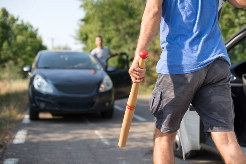 man with a stick is going to assault another driver opposite him blocking the road